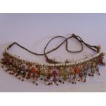 An Indian yellow-metal fringe necklace set with a multitude of semi-precious stones, coral etc., and