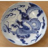 A blue and white bowl, late Ming, painted in underglaze blue with a dragon in clouds, rim frits, Gen