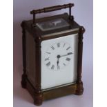 A late 19th century brass and glass-sided carriage clock with key, the white-enamel dial with