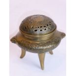 A Chinese brass tripod censer the two handles modelled as mythical beast heads and the pierced cover