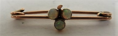 A rose gold safety pin brooch set with three opals