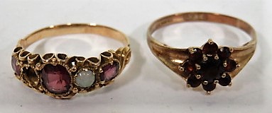 A gold and red stone flower ring with faded hallmarks together with an amethyst and opal ring, on an