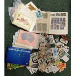A small stamp album containing a collection of world stamps, together with some loose cigarette
