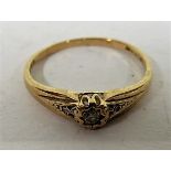 A 9ct gold solitaire and diamond ring with a diamond chip to each shoulder and faded markings,
