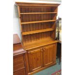 A narrow pine dresser, four shelves above two doors below with shelf 186 x 107 x 33