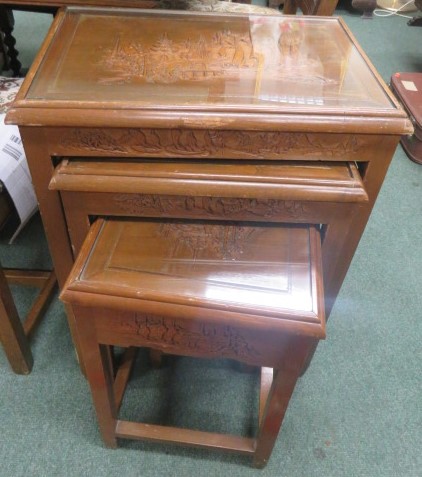 A nest of four oriental tables with carved junk top covered by glass 66 x 50 x 35