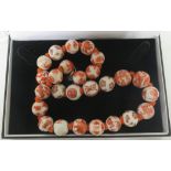 A Chinese porcelain orange and white bead necklace