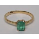 A marked 18ct gold dress ring set with a step cut emerald, measuring approximately 5.8mm x 4.8mm,