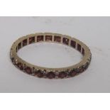An unmarked yellow metal garnet eternity ring, ring size M, weight 1.4g