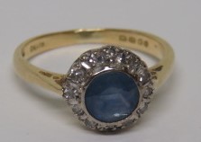 An 18ct gold diamond and light cornflower blue sapphire halo ring, with faded hallmarks, the