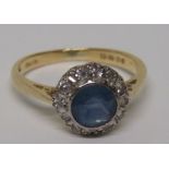 An 18ct gold diamond and light cornflower blue sapphire halo ring, with faded hallmarks, the
