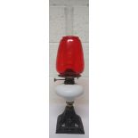 Victorian cast iron oil lamp with a glass reservoir, together with a chimney and a red shade, 52cm