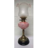 Brass oil lamp with column support, with a pink glass reservoir and together with a chimney and a
