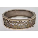 A Victorian silver bangle with an openwork front panel of gilt carved leaves, the bangle is