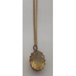 An oval faceted lemon citrine pendant in an unmarked gold (tested) surround on a yellow metal fine
