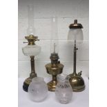 Three Victorian brass oil lamps with all three lacking shades together with two spare shades