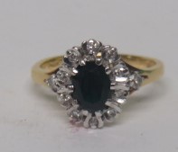 A marked 750 gold diamond and dark blue sapphire cluster ring, the sapphire length approximately