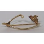 A marked 15ct gold wishbone brooch set with a seed pearl to one end, and a carved bird with pink