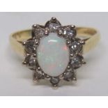 A marked 750 gold diamond and opal cluster ring, the opal length approximately 8.5mm, ring size M