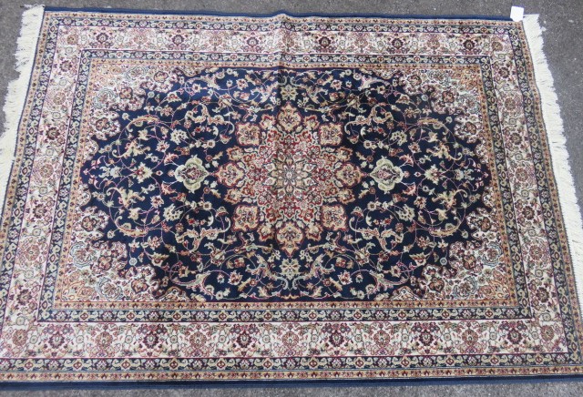 A new silk and wool rug with a blue and cream ground with a blue border and decorated with flora and