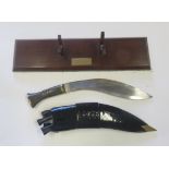 A post war Kukri, blade marked 65E. Brass mounted wood handle with patent leather type scabbard.