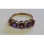 A vintage marked 9ct rose gold dress ring set with five coloured stones in purple, orange and red,