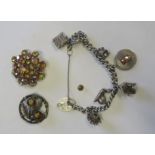 A silver charm bracelet, weight 53g, together with two costume brooches