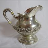 A white metal jug with embossed decoration to base and middle. Indistinguishable foreign markings,