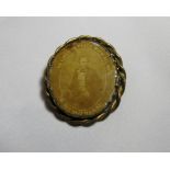 An early 20th century oval in memoriam brooch, glass photo front with a gilt metal twist mount, C