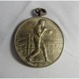 A white metal medal depicting an embossed boxer in the ring, adapted for pendant. Diameter 30mm,