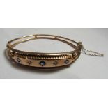 A marked 9ct gold diamond and sapphire bangle - diameter 6cm, weight 7.2g.