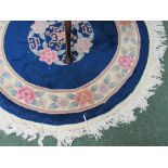 A predominantly deep blue, pink and green circular fringed rug of oriental design approx. 102cm in