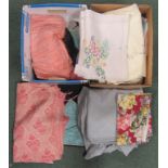 Two boxes of textiles to include bed spreads and table wares.