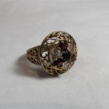 A 9ct gold 7 stone garnet and clear paste circular Boule ring with an open work surround measuring