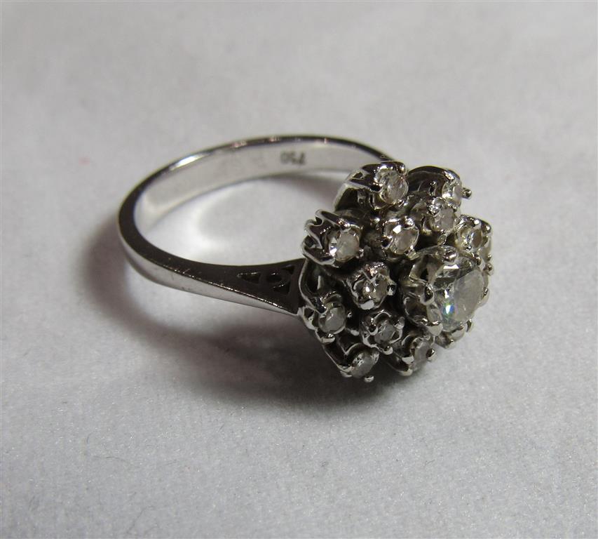 A marked 750 white gold diamond cluster ring with the cluster shaped as a tiered flower comprising