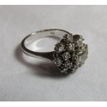 A marked 750 white gold diamond cluster ring with the cluster shaped as a tiered flower comprising