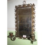 A metal trailing leaf framed mirror with two candlesticks
