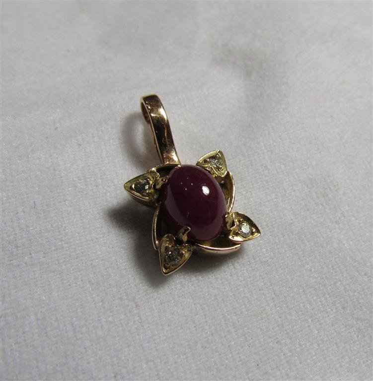 An unmarked Indian gold star ruby and diamond accent pendant piece with the oval cabochon ruby