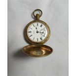 A gold tone metal small vintage full hunter pocket watch with engine turned design to the case. Face