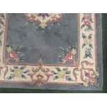 A predominantly grey/blue, green and pink rug of oriental design on a cream background, 150cm x 90cm