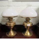 A pair of brass paraffin lamps with white glass shades and clear funnels