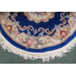 A deep blue, pink, green and cream fringed circular oriental design rug, 102cm diameter approx.