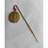 An unmarked gold or gilt hat pin with an attached oval locket with floral engraving and opens to