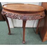 An oval occasional table of oriental design and with a carved dragon design skirt to top