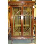 An oriental style glass fronted mahogany bookcase and on a carved plinth and legs with key