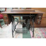 A Jones pedal sewing machine cabinet with four drawers and sewing machine under hinged lid