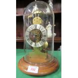 A modern pendulum clock with roman numerals under a glass dome