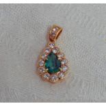 EMERALD AND DIAMOND PENDANT WITH PEAR SHAPED EMERALD IN A CLAW SETTING FRAMED BY ROUND BRILLIANT