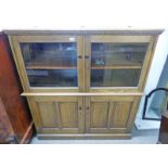 20TH CENTURY OAK CABINET WITH LIFT UP TOP OVER 2 GLAZED DOORS OVER 2 PANEL DOORS ON PLINTH BASE
