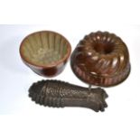 A Victorian pottery jelly mould; a copper example; and a later fish form example